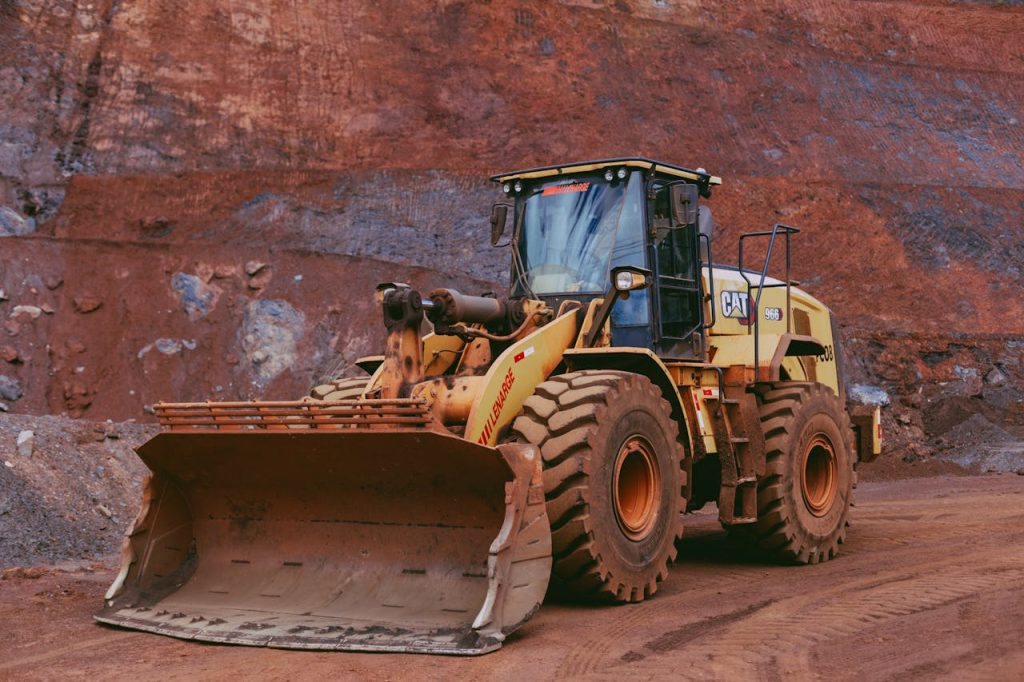 Large yellow bulldozer operating in a mining quarry with rugged terrain.