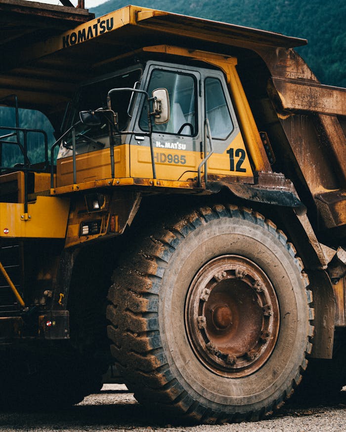 Close-up of a large yellow dump truck used in mining, highlighting its robust build and giant wheels.